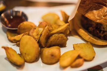 Hamburguesa con patatas y colas de queso en restaurante
