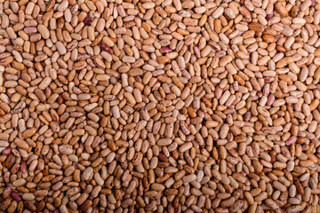 Natural background of many fresh organic red beans in a plastic box in warm light, top view or flat lay of organic vegan food photographed with soft focus.