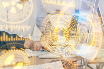 Technology theme hologram with man working on computer on background. High tech concept. Multi exposure.
