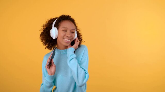 funny cute mixed race woman she listens to music in the earpiece and sings with her phone.