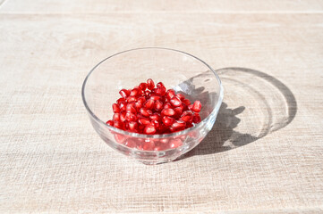 A bowl of pomegranate seeds in sun light with its shadow.