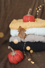 Autumn cozy still life with handmade pumpkin, sweaters, leaves and warm lights. Thankgiving or Halloween concept