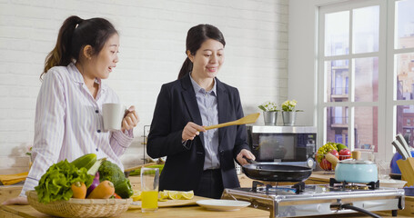Two attractive asian japanese women friends preparing early healthy meal in modern kitchen together...