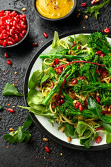 Tenderstem broccoli and egg noodles Asian style vegetarian salad with roasted pine nuts and pomegranate seeds