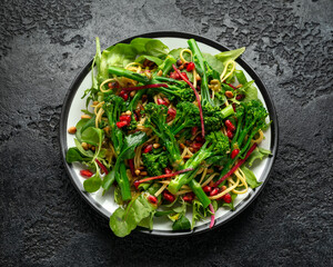 Tenderstem broccoli and egg noodles Asian style vegetarian salad with roasted pine nuts and pomegranate seeds