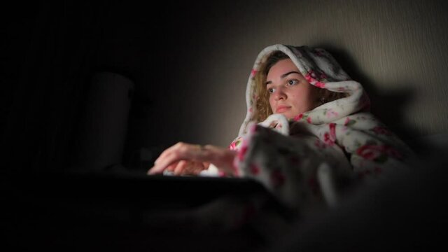 Freelancer or blogger woman in bathrobe working by laptop PC at night
