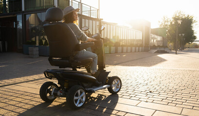 Woman tourist riding a four wheel mobility electric scooter on a city street.	