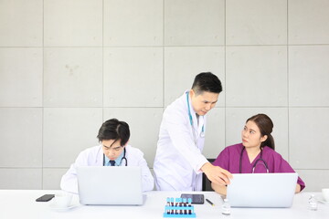 Senior doctor sharing advice in health care and patient examination during the medical meeting with other doctors using laptop computer