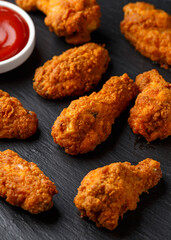 Spicy deep fried Chicken wings with ketchup on stone board