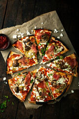 Delicious pizza with goat cheese and pesto sauce, mushrooms and prosciutto. - 387777502
