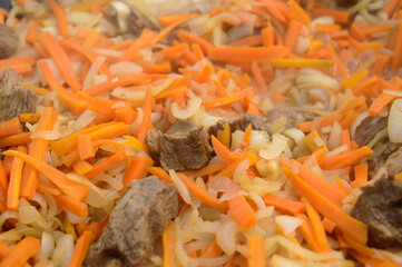 meat in a cauldron with carrots and onions