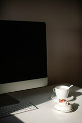 Home interior. Work desk with a computer, a cup of coffee and a sweet dessert.