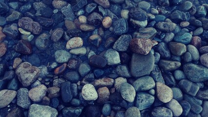 FONDO DE PIEDRAS MOJADAS EN PLAYA DEL SUR PATAGONICO, TONOS GRISES Y AZULADOS, BARILOCHE, RIO NEGRO, ARGENTINA