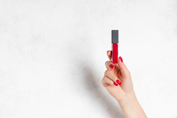 red liquid matte lipstick in female hand with red manicure. Beauty Cosmetics, Makeup Concept. white background with copy space