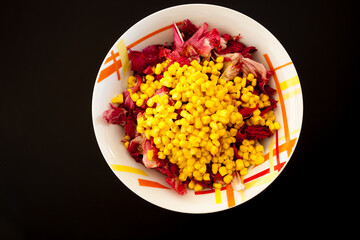 Salad with corn on black table, top view