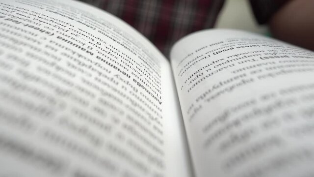 Close up panning video of an open book. Selective focus on example text book. Class notebook. Motion in the middle of a book with an example text.