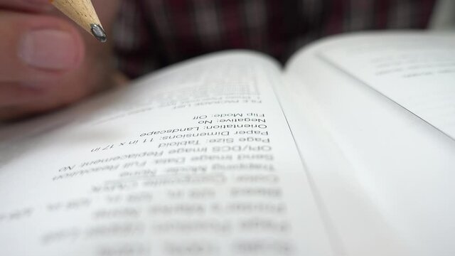 Young university student marking the important words from his lectures. Class notebook. Selective focus on example text book. Close up on student hands studying and doing homework.