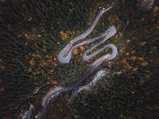 Winding road from the high mountain pass in Cheile Bicazului, Romania. Great road trip trough the dense woods. Aerial view with autumn colors