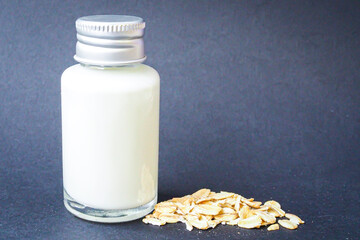Small glass bottle with oat milk and oats