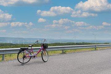 people parking bicycle on road of power plant that generate renewable energy from wind turbines