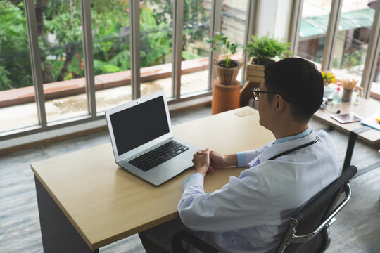 Young Asian Doctor Using Computer In Hospital Office. Healthcare And Medical Concept