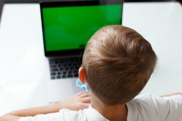 a child in a medical mask with a laptop at home in quarantine training online