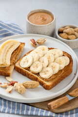 peanut butter banana sandwich in a white plate on gray background
