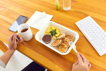 Hands of office worker eating healthy balanced meal from container in office