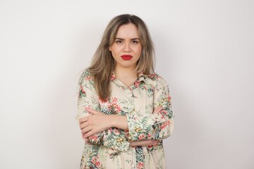 Waist-up portrait of beautiful girl frowning her face in displeasure, wearing casual clothes, keeping arms folded, waiting for an explanation. Attractive young woman in closed posture.