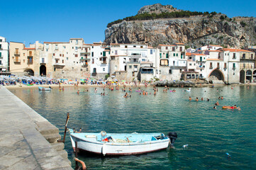 Fototapeta na wymiar Characteristic view of the coastal city of Cefalù near Palermo in Sicily. It has a cristal clear blue water and nice old houses in front of the sea 
