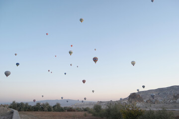 Panoramic view of hot air balloons flying over mountains. Ballooning at Goreme National Park. Cappadocia, Turkey.