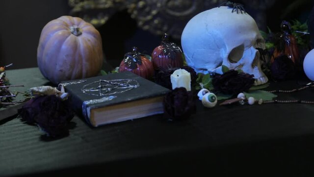 Focus change and smooth camera movement. Close-up of a black book with a pentagram and a human skull. The concept of a witch's table for rituals on the eve of halloween. 
