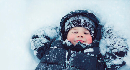 Happy little boy lying on the snow