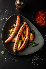 Grilled sausages with fried potatoes, rosemary and basil on a plate