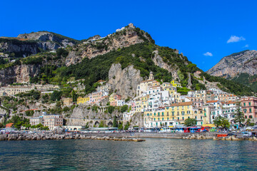Fototapeta premium View of the city of Amalfi from the jetty with parked buses, the sea and the colorful houses on the slopes of the Amalfi coast in the province of Salerno, Campania, Italy.