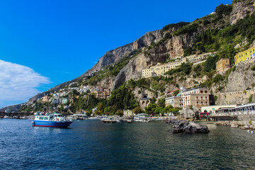 Fototapeta na wymiar View of the town of Amalfi from the jetty with, the sea, boats and colorful houses on the slopes of the Amalfi coast in the province of Salerno, Campania, Italy.