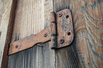 Old and rusty door hinge holding a wooden gate closed