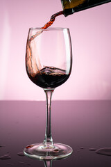 splash of red wine in glass on red background