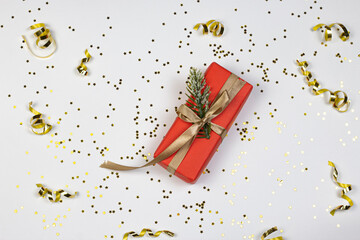 Gift box with golden ribbon and bow, glitter stars and golden confetti on white background. Party time concept. Flat lay.