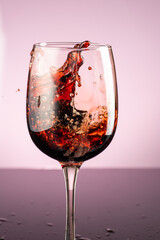 splash of red wine in glass on red background