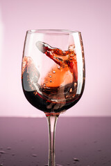 splash of red wine in glass on red background