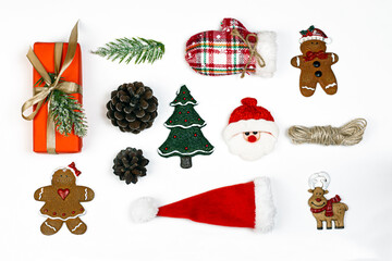 Gift box, Christmas candy, fir cone, decorative Christmas tree toys, Santa Claus hat and gloves.  Flat lay on white background. Party time concept.