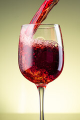 splash of red wine in glass on yellow background
