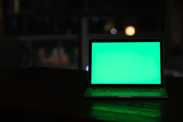 front view of green screen laptop computer at dark night.