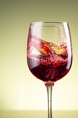 splash of red wine in glass on yellow background