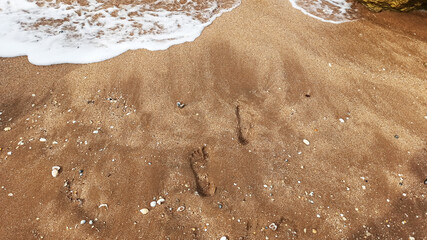 footprints on a sandy beach next to the sea
