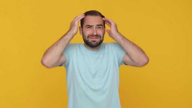 Shocked bearded young man 20s in basic casual blue t-shirt isolated on yellow background studio. People sincere emotions lifestyle concept. Looking at clock watch gets nervous realizes that he is late