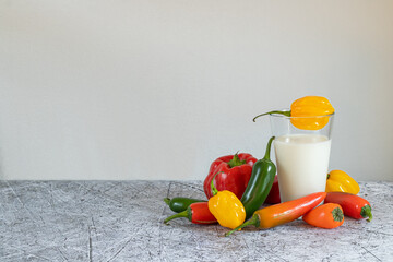 A glass of milk surrounded by colorful peppers and a place for text