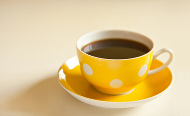 cup of black tea on yellow plate. yellow cup with dots. retro style. vintage mug
