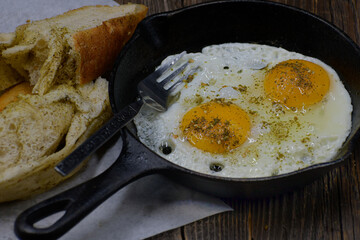 Fried eggs seasoned with zaatar in cast iron pan, along with zaatar bread